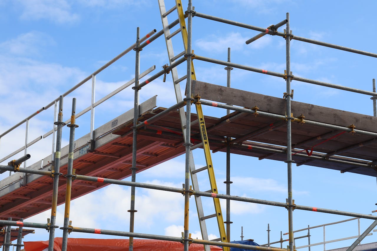 home-hero Detailed view of a construction site scaffolding structure and ladder against a bright blue sky.